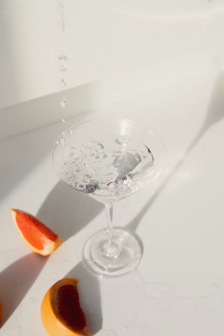 Wine Glass Filled With Clear Liquid on White Surface 